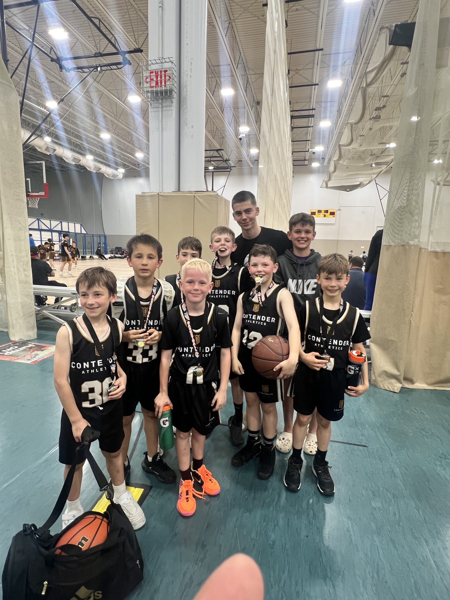 Youth basketball team posing with trophies indoors.
