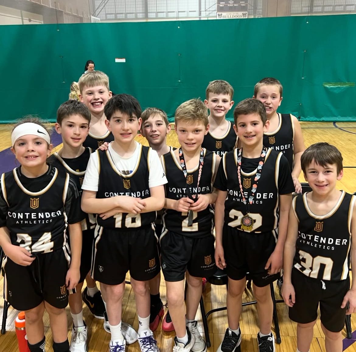 A youth basketball team posing together in their black uniforms.