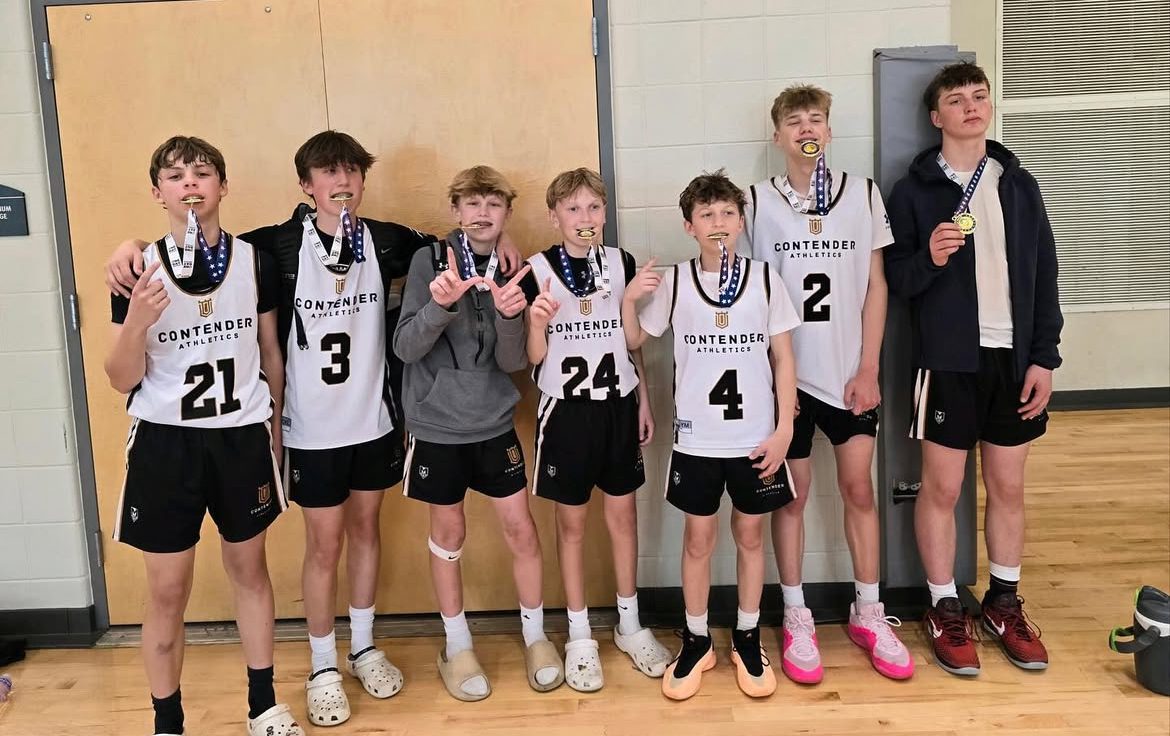 Youth basketball team posing indoors with medals and trophies.