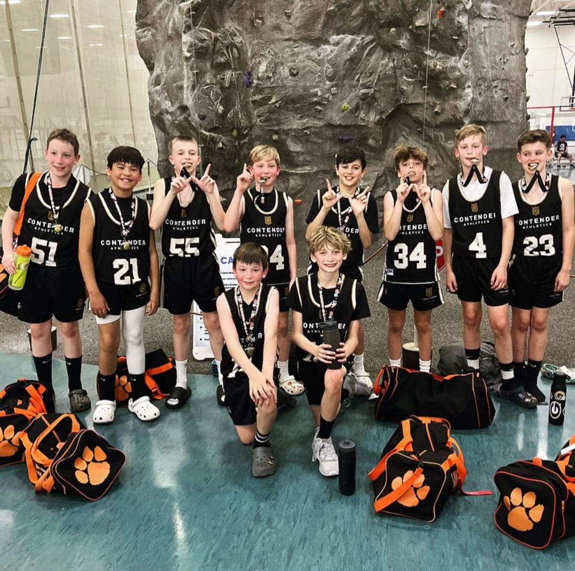 Youth basketball team posing indoors with medals and uniforms.