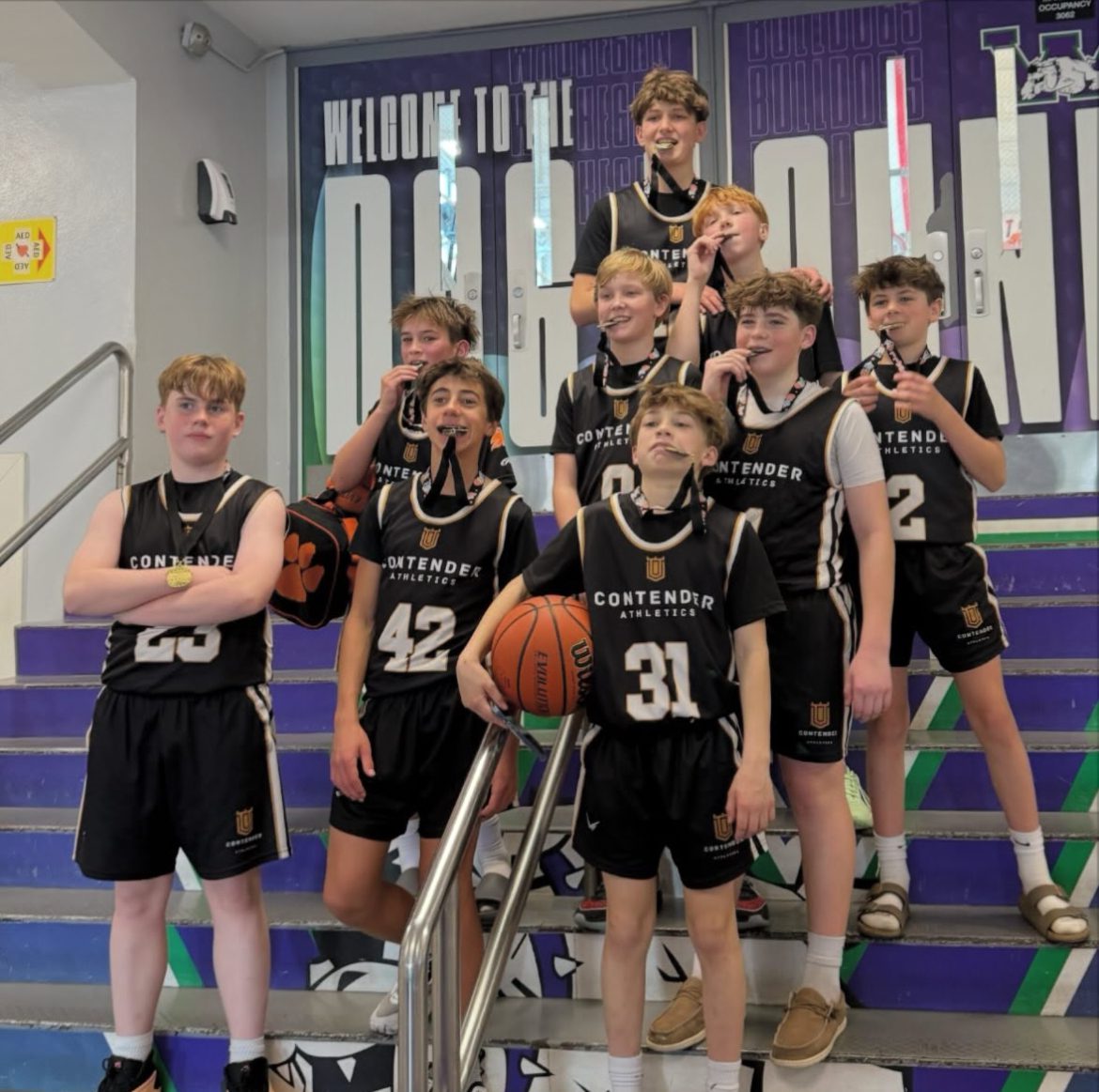 Youth basketball team posing confidently on stairs in their black uniforms.