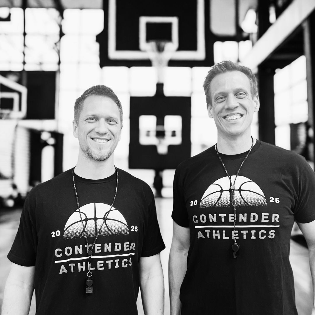 Two men smiling in matching Contender Athletics shirts at a basketball court.